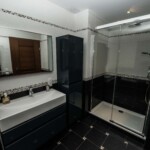La salle de bain avec douche et baignoire balnéo